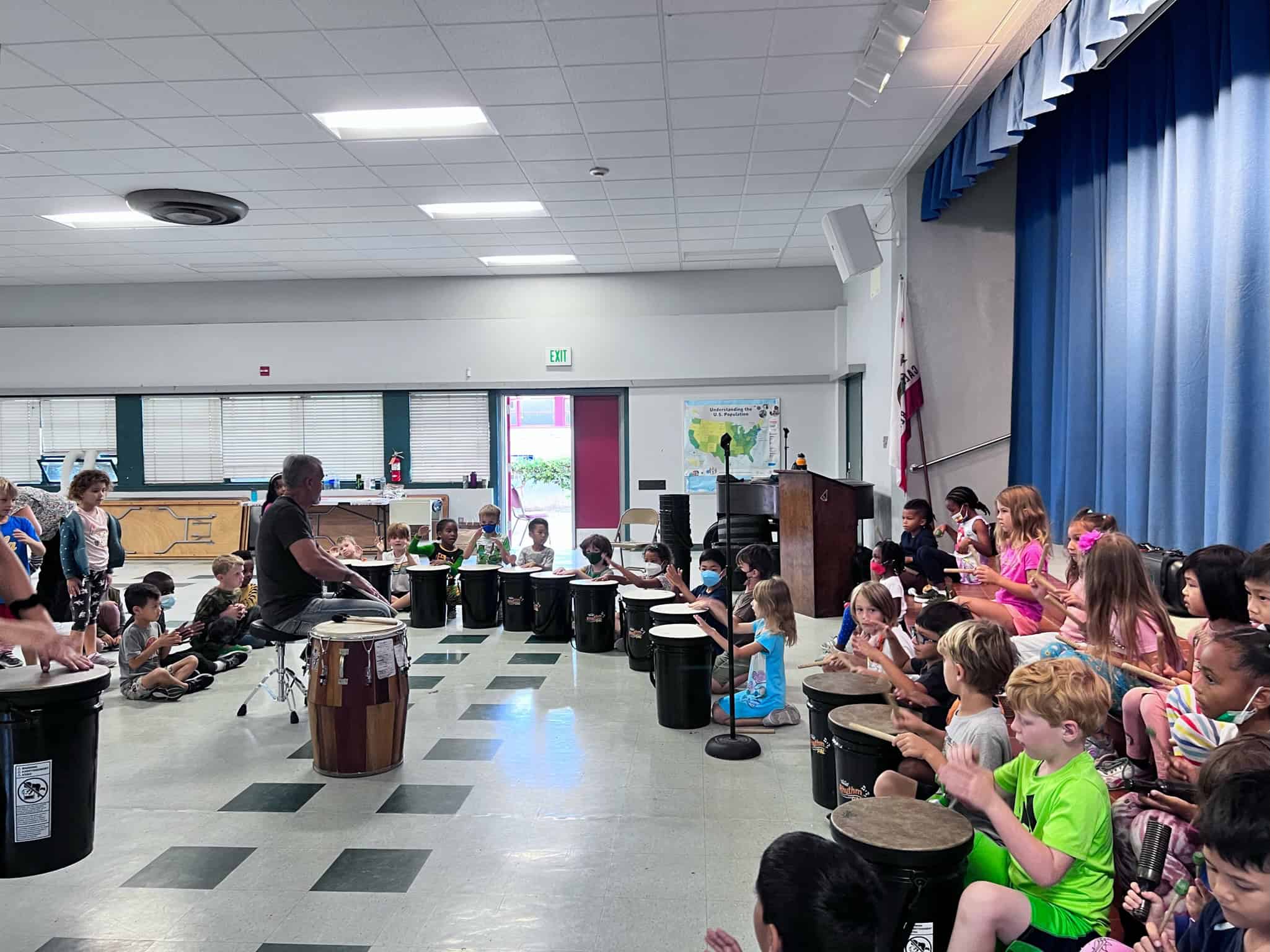 Eight students performing on drums at school assembly