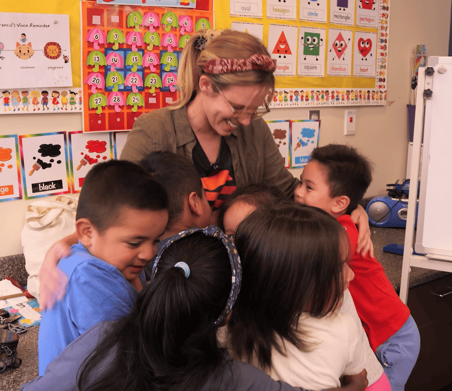 Students hugging teacher